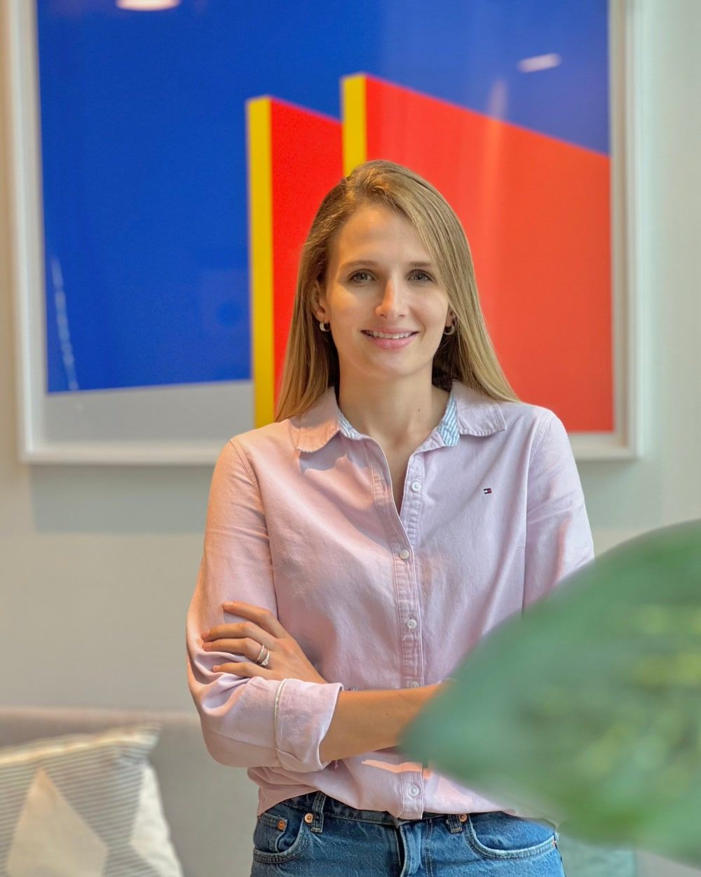 Irene Rosich de pie frente a un cuadro geométrico azul y rojo.